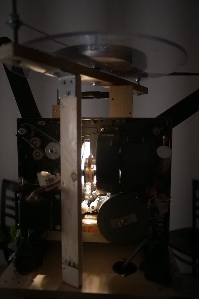 ”Katsovatko puut meitä?” | tilataideteos | 16 mm filmi, digitaalinen video ja ääni, huonekasvi, sekatekniikka | 2025